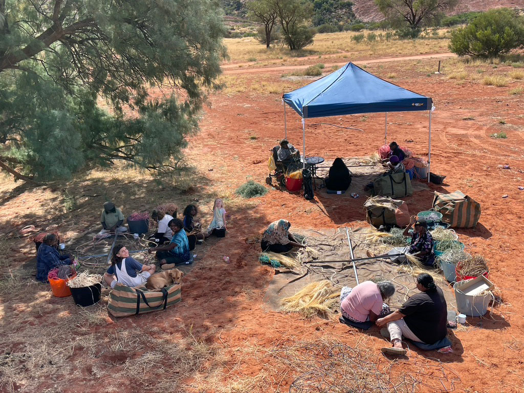 A number of the artists are sitting on the ground in the open and working on the art pieces in smaller groups.