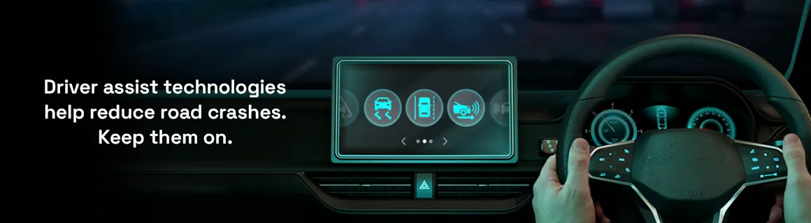 Image of hands on a driving wheel and driver assist technologies displayed on a large display.