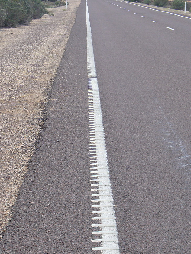 A closeup of tactile line markings on a highway.