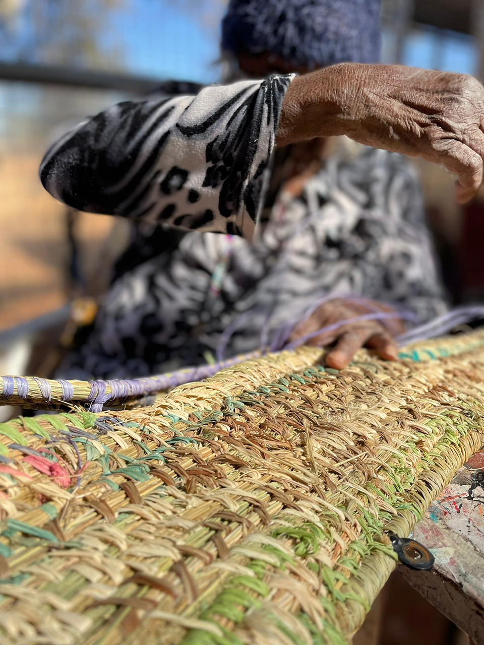 A weaver works on one of the artworks.