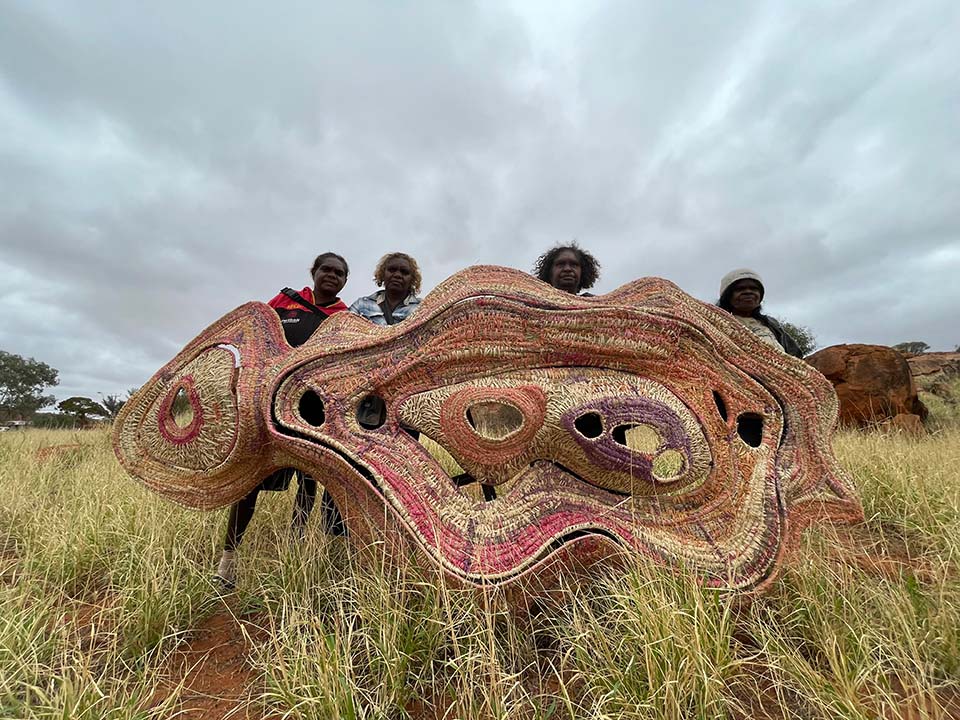 Four artists hold up a finished artwork.