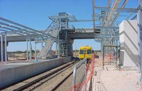 Construction of Elder Smith Road bridge over the railway lines, plus the Mawson Lakes Interchange platform and elevator tower with oncoming train in January 2006. 
